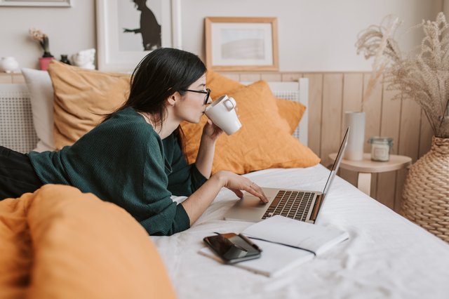 woman-using-laptop-and-drinking-beverage-in-bed-4050415.jpg